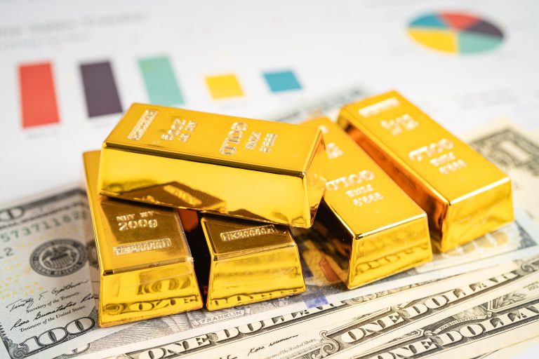 Emas batangan di atas uang kertas dolar AS dan grafik